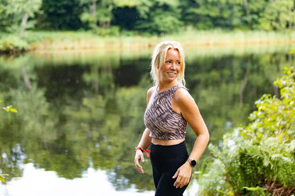 Kvinna vid spegelblank sjö i grönska